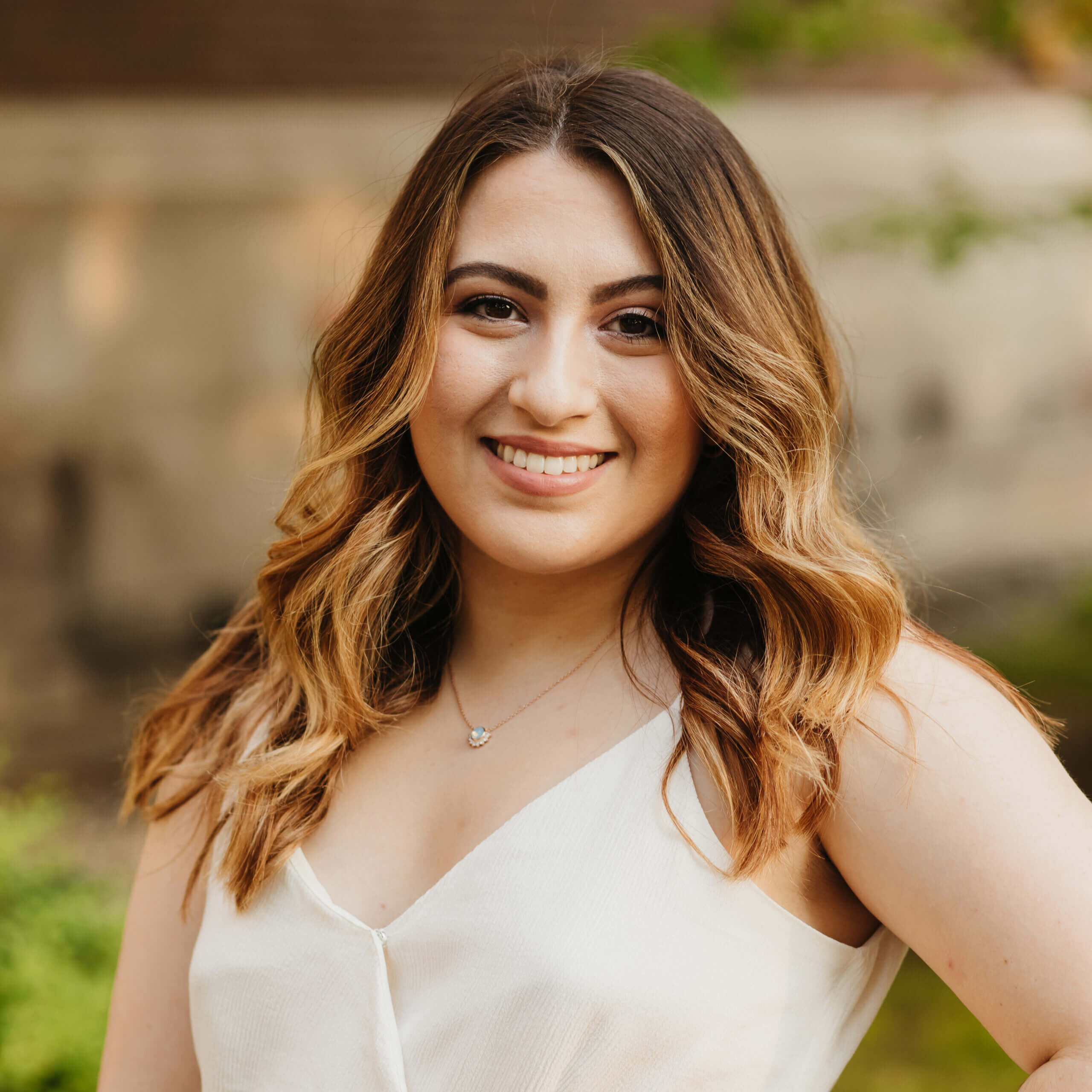 This photo is of Jess Giusti, our Media Marketing Manager. She's a white woman (Italian heritage), smiling, she has brown hair<br />
 that is highlighted and she's wearing a pretty white dress.